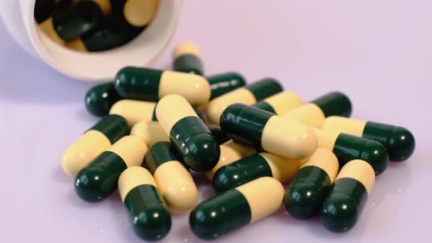 Un sacco di pillole mediche per il trattamento in capsule verdi gialle su una tavola rotante. Primo piano di medicinali, vitamine, farmaci. - Filmati, video