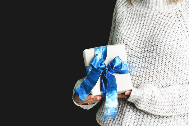 La chica sostiene un regalo con un lazo azul en las manos. Regalo en papel artesanal. Hermoso arco azul. Un regalo de Navidad. Año Nuevo. Sorpresa. - Foto, Imagen