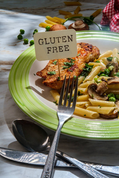 Italian penne alfredo with spinach mushrooms and peas served with grilled chicken breast with glass of white wine and parsley garnish - Photo, Image
