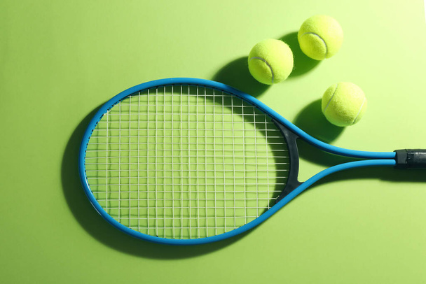 Tennis racket and balls on green background, flat lay. Sports equipment - Fotó, kép