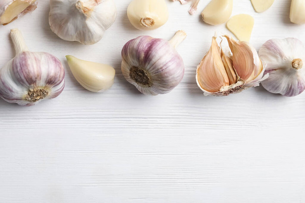 Fresh organic garlic on white wooden table, flat lay. Space for text - Фото, зображення