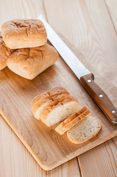Pan de cerca (pan largo) sobre tabla de cortar madera, cuchillo - Foto, imagen