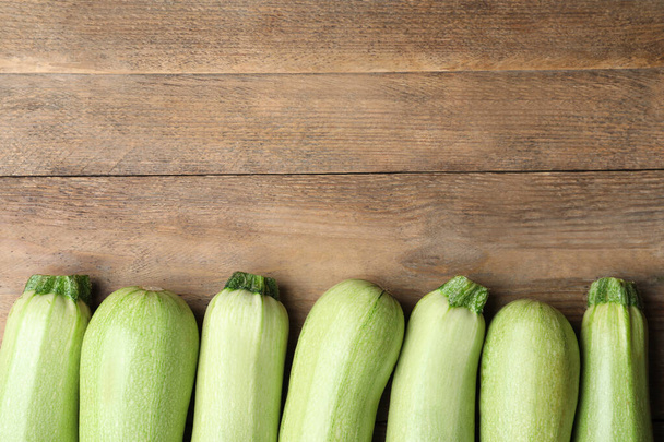 Raw green zucchinis on wooden table, flat lay. Space for text - Valokuva, kuva