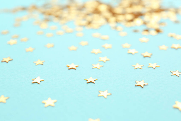 Confetti stars on light blue background, closeup. Christmas celebration - 写真・画像