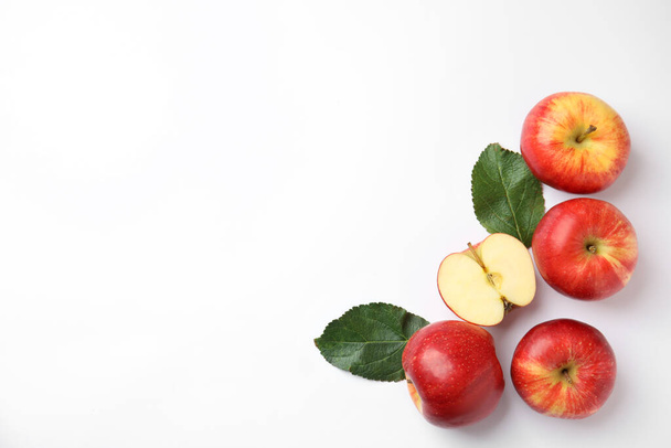 Fresh ripe red apples and leaves on white background, flat lay. Space for text - Valokuva, kuva