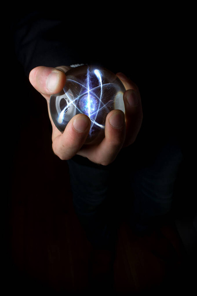 Holding atom in fortune teller magic crystal ball - Photo, Image