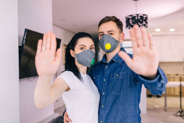 a guy and a girl in medical protective masks on their faces, standing with an outstretched hand, showing a gesture to stop the virus. - Photo, image