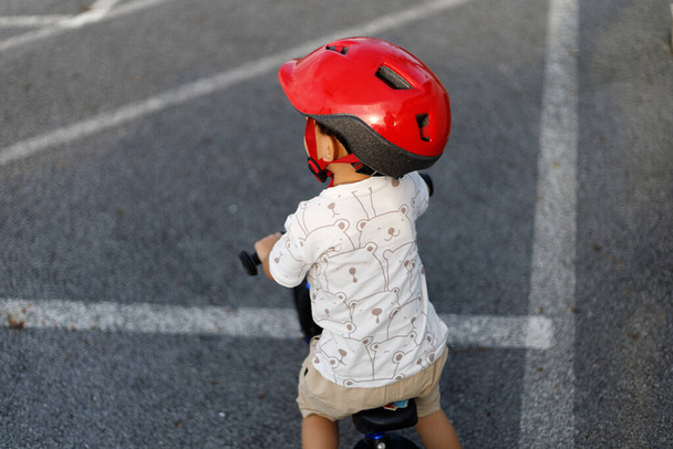Schattige Aziatische jongen (peuter leeftijd van 1 jaar oud), het dragen van een veiligheidshelm en leren fietsen in de speelruimte. Baby Speeltuin en Veilige Plaats Concept. Portret foto met kopieerruimte. - Foto, afbeelding