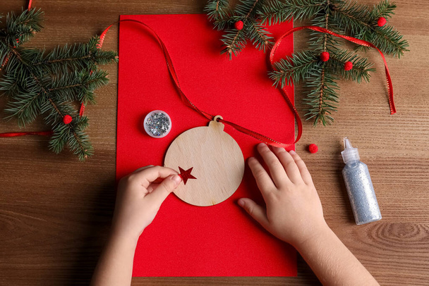 Little child making Christmas card on wooden table, top view - Foto, imagen