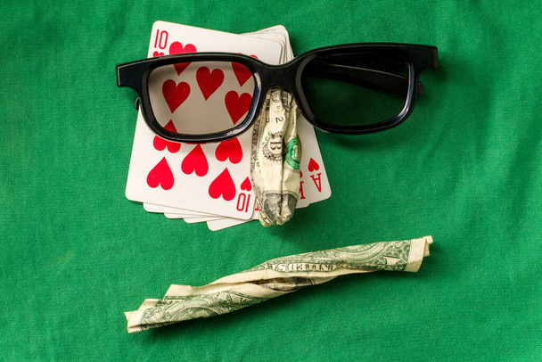 Глупая метафора покерного лица, сделанная из различных игровых предметов, включая деньги и карты - Фото, изображение