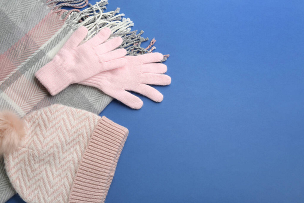 Stylish gloves, scarf and hat on blue background, flat lay. Space for text - 写真・画像