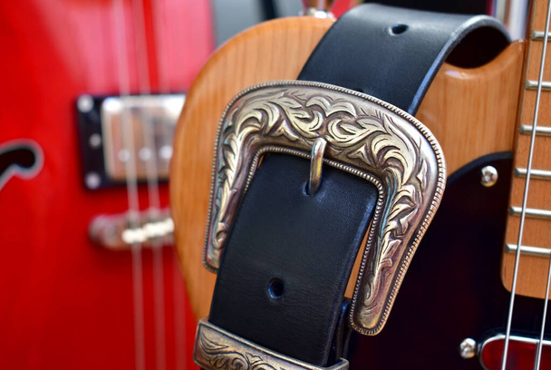 Ηλεκτρικές κιθάρες και δερμάτινο λουράκι με ασημένια πόρπη close-up. - Φωτογραφία, εικόνα