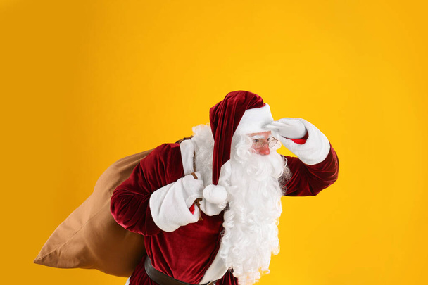 Portrait of Santa Claus with sack on yellow background - Zdjęcie, obraz