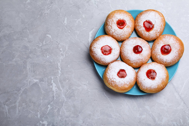 Hanukkah doughnuts with jelly and sugar powder on grey marble table, top view. Space for text - Фото, изображение