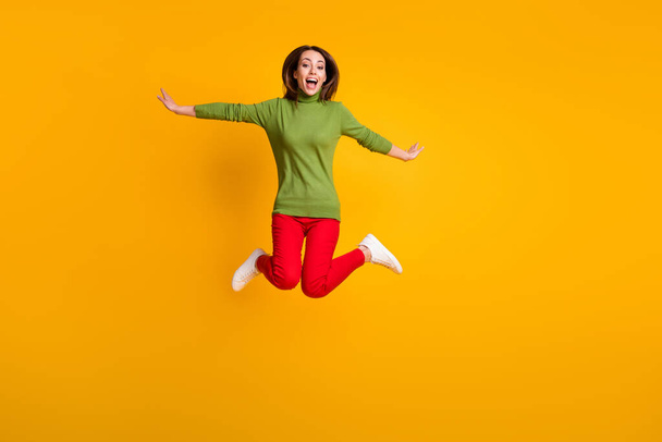 Full body photo of lady jump up air flight rejoicing wear casual pullover sneakers red trousers isolated yellow color background - Foto, Imagen