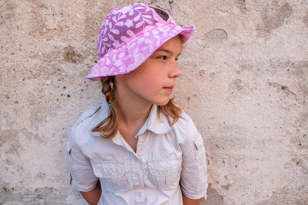 Pembe şapkalı güzel genç kız taş duvarın yanında duruyor.. - Fotoğraf, Görsel