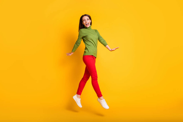 Full size profile photo of funny lady jump up walking wear green pullover sneakers trousers isolated yellow color background - Photo, Image