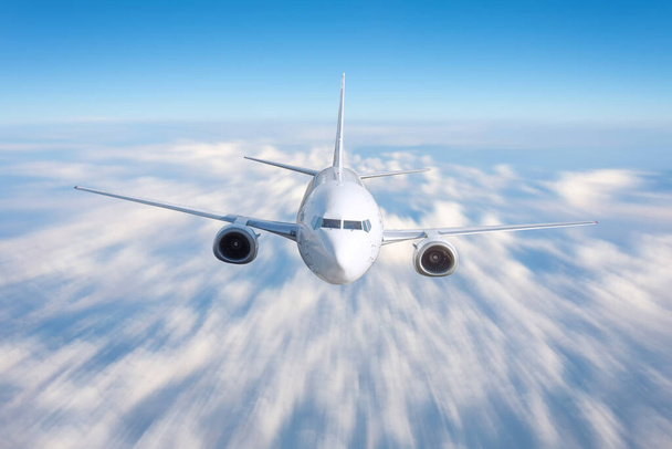 Repülőgép repül gyorsan a felhők felett magasan az égen, az elülső nézet egyenes - Fotó, kép