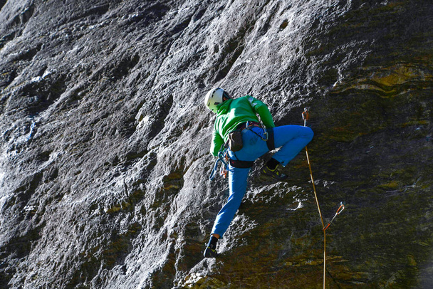 Un uomo che si arrampica legato con una corda ai moschettoni sulla grande parete - Foto, immagini