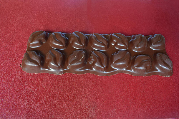 Čokoládová tyčinka s náplní na červeném pozadí zblízka. - Fotografie, Obrázek