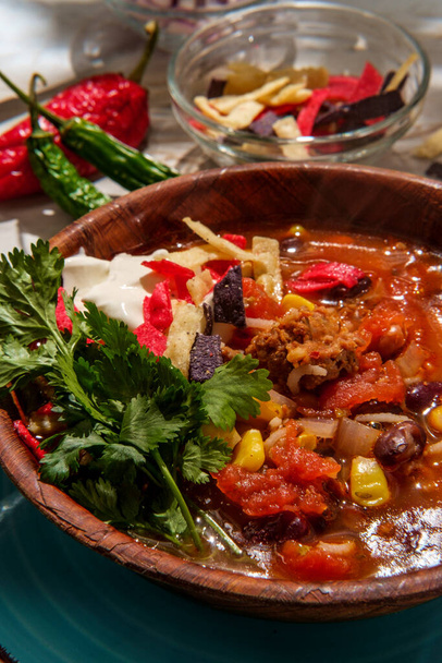 Meksykańska zupa taco z kiełbasą chorizo z fasolą pinto i fasolą nerkową podawana z kieliszkiem czerwonego wina - Zdjęcie, obraz