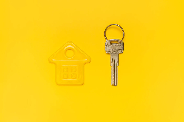 House symbol and metal keys on yellow background flat lay top view copy space. House door keys. Concept of buying home, apartment. Renting a house, real estate. Mortgage, credit, real estate insurance. - Fotografie, Obrázek