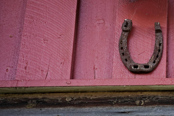 Sapato de cavalo enferrujado velho em uma parede de celeiro vermelho para a boa sorte. Foto de alta qualidade - Foto, Imagem