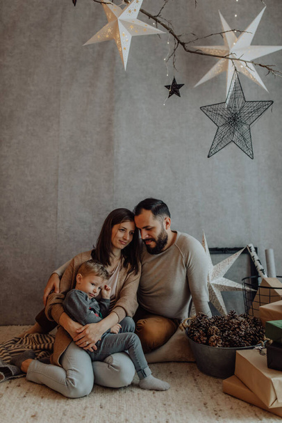 Young family with a cute boy spend intimate moments in the holiday decor at home. - Fotó, kép