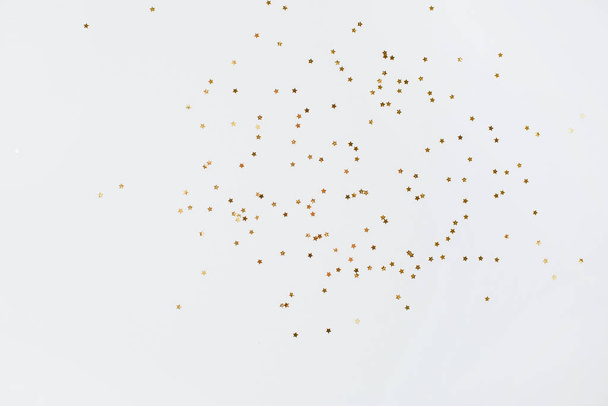 Spangles of gold and silver are scattered from bottles on a white background - Foto, Imagen
