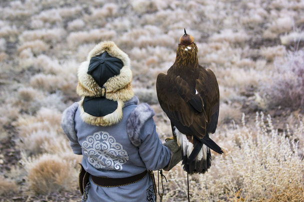 a hunter with an eagle is waiting for prey on a hill - Photo, Image