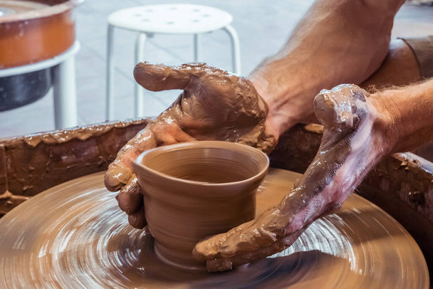 Handen van een man Potter beeldhouwwerk faience op een pottenbakkerswiel. Begrip natuurlijke materialen, handgemaakt en creatief. - Foto, afbeelding