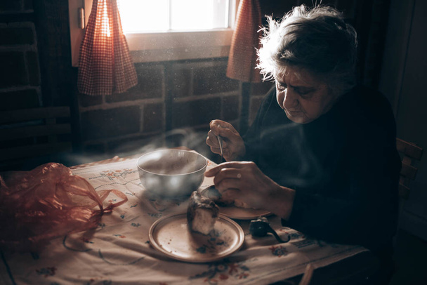 Elderly woman sitting alone at the table, eating a meal - Photo, Image