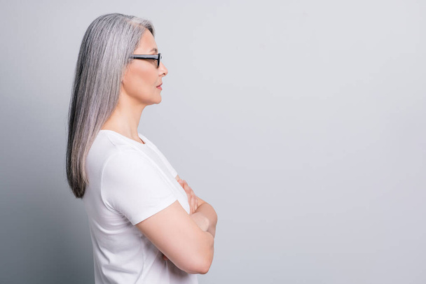 Profile photo of retired woman look empty space crossed arms wear spectacles white t-shirt isolated grey color background - Valokuva, kuva