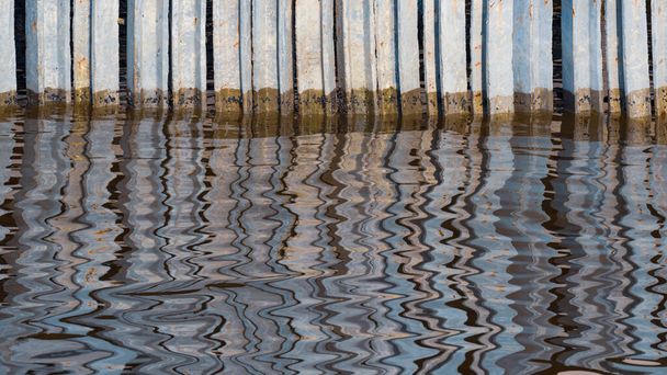 Reihe von Betonpfählen entlang der Küste zum Schutz der Küstenerosion mit verschwommenen, abstrakten Bewegungsmustern der Reflexion auf der Meeresoberfläche - Foto, Bild