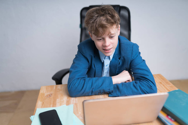 A portrait of a Caucasian teenage boy in blue school uniform listening a lecture during online classes. Education concept - Foto, immagini