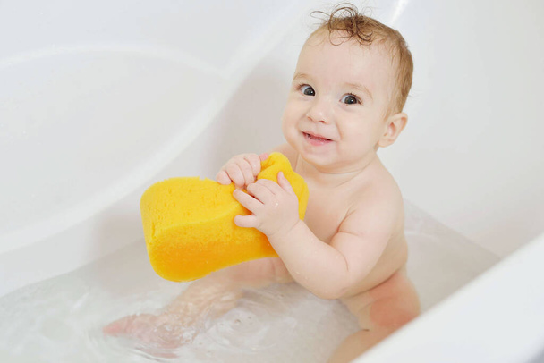 mouillé gamin se livre dans la salle de bain. C'est l'heure de tremper dans la baignoire. Bébé heureux ayant un bain et souriant. - Photo, image