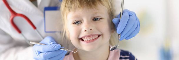 Маленькая девочка улыбается стоматологу крупным планом - Фото, изображение