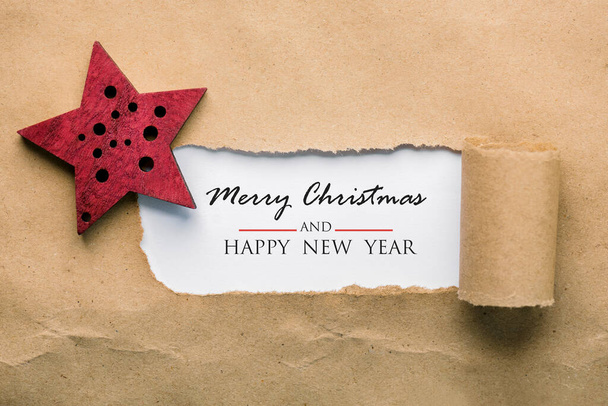 Mutlu Noeller ve kırmızı noel yıldızlı yeni yıl mesajı içeren yırtık kağıt. Noel konsepti geçmişi. - Fotoğraf, Görsel