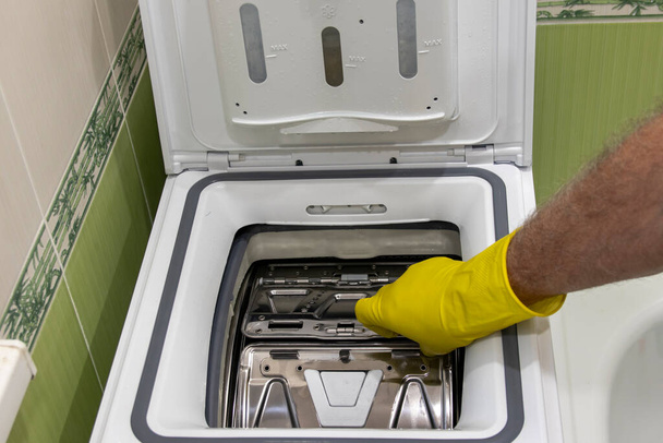 Close-up da mão de um homem abrindo uma máquina de lavar roupa de carregamento superior. Conceito de rotina doméstica. - Foto, Imagem