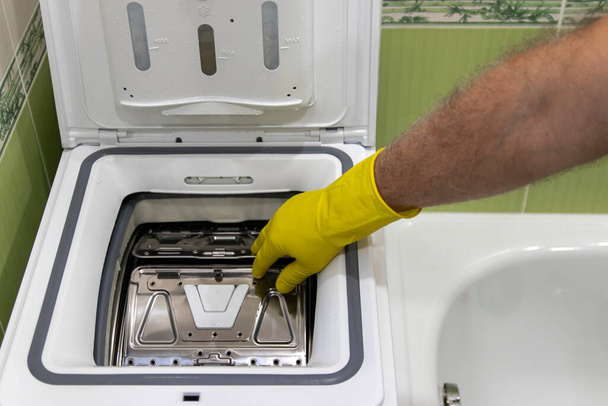Рука людини, що відкриває пральну машинку з верхнім завантаженням
 - Фото, зображення