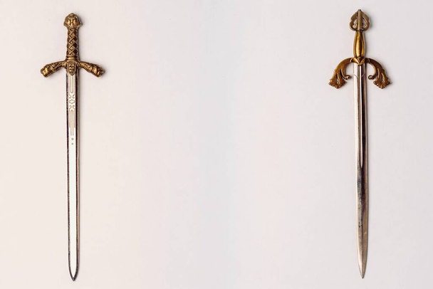Dwa starożytne miecze rycerskie ze złotymi wzgórzami z grawerem odizolowanym na białym tle. Pozycja pozioma, przestrzeń kopiowania - Zdjęcie, obraz