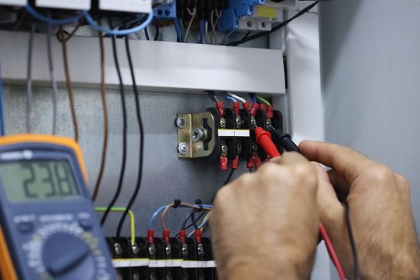 An electrical technician measures the voltage at the terminals using probes.Close up - Photo, Image