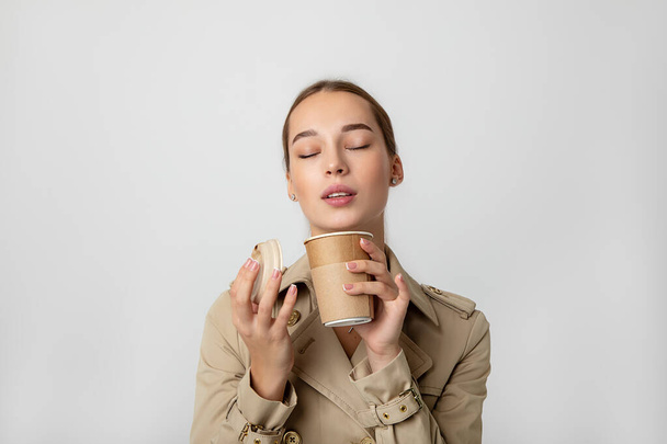 joven mujer de belleza disfrutando de café bebida caliente de la taza ecológica reciclable desechable. Estudio primer plano retrato - Foto, Imagen