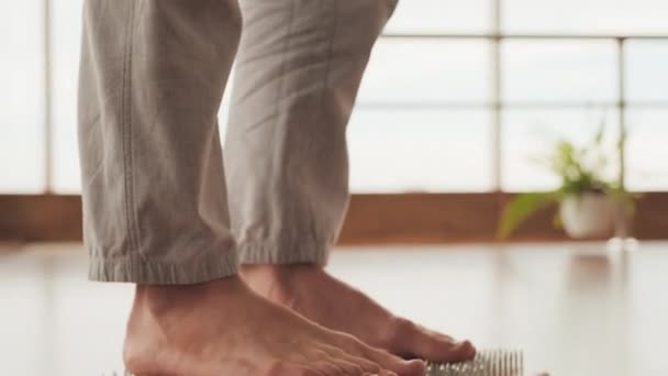 Kippen von den Zehen bis zum Kopf Filmmaterial junger professioneller Yogi, der barfuß auf Nägeln steht und im Fitnessstudio meditiert - Filmmaterial, Video