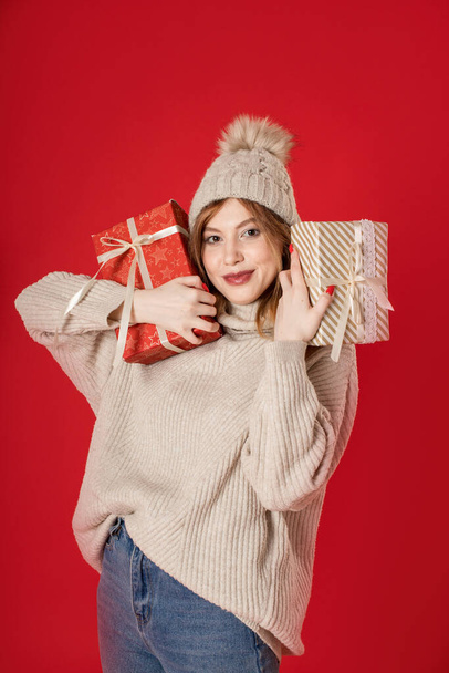 Dreaming winter girl holding Christmas gifts on background. - Фото, изображение