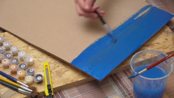 Karton üzerine suluboya çizimler - bir kız mavi bir arkaplan çizer, boya ve fırçalara yakından bir bakış, evde yaratıcı aktiviteler - Video, Çekim