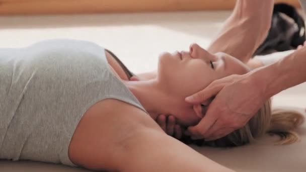 Close up de jovem deitado no chão com os olhos fechados recebendo massagem no pescoço após o treino duro - Filmagem, Vídeo