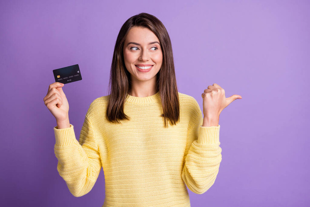 Photo portrait of beautiful girl keeping bank plastic card showing on empty space smiling looking at side isolated on bright purple color background - Foto, immagini