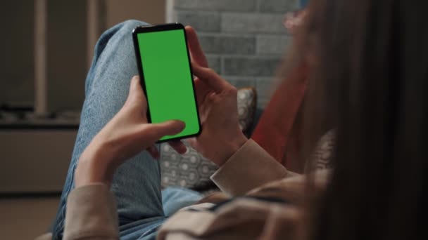 Close up Nő otthon használ okostelefon zöld Mock-up képernyő, csinál lopás, görgetés gesztusok. Mobiltelefont használó nő, internetes közösségi hálózatok böngészése. Nézőpont Camera Shot - Felvétel, videó