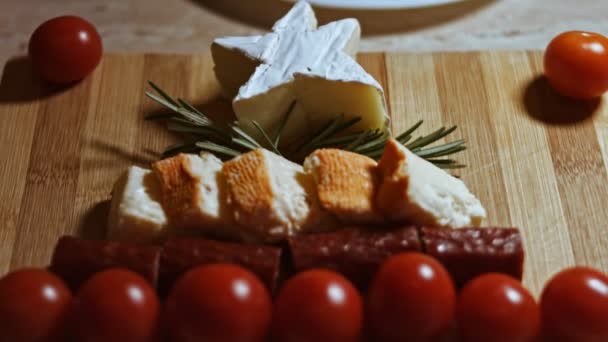 Flat lay of cheese and meat platter. Slices of cheese, smoked sausage, tomatoes, olives and rozmarin arranged in a shape of Christmas Tree. Food for Christmas holiday. Macro view - Footage, Video